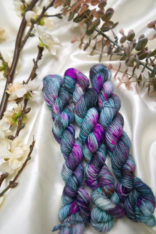 custom variegated hand dyed yarn with grey, black, and teal with neon purple speckles on nylon superwash sock weight