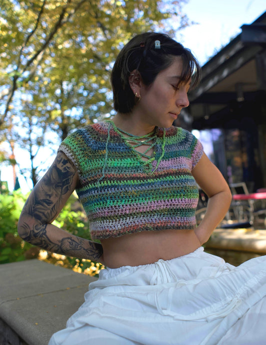 Erin wearing a colorful v-neck crochet top featuring a raglan design and laced center.