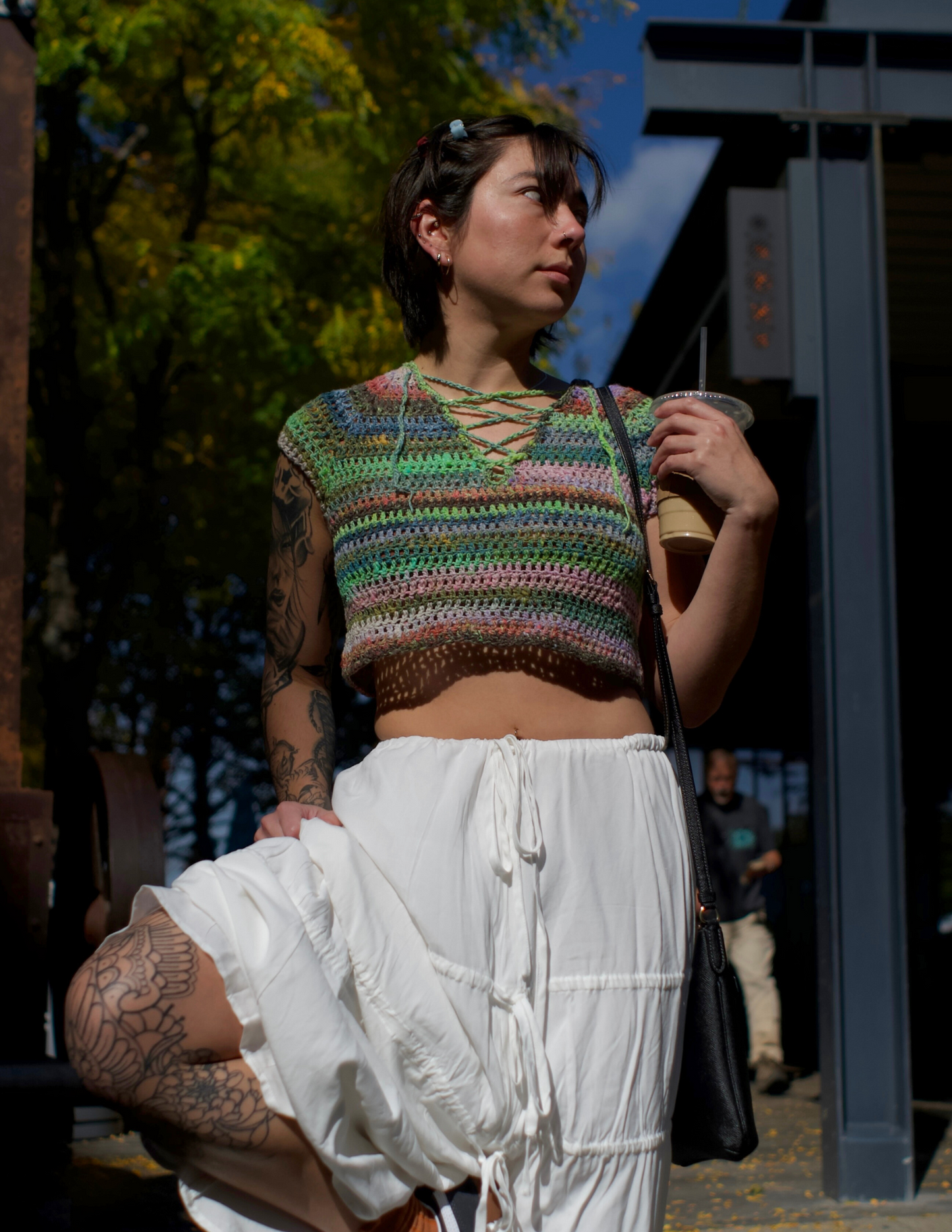 Erin wearing a colorful v-neck crochet top featuring a raglan design and laced center.