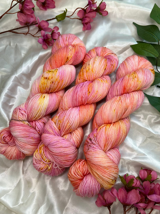 variegated hand dyed yarn in corals, pinks, and pastel orange with fawn brown speckles on nylon sock fiber
