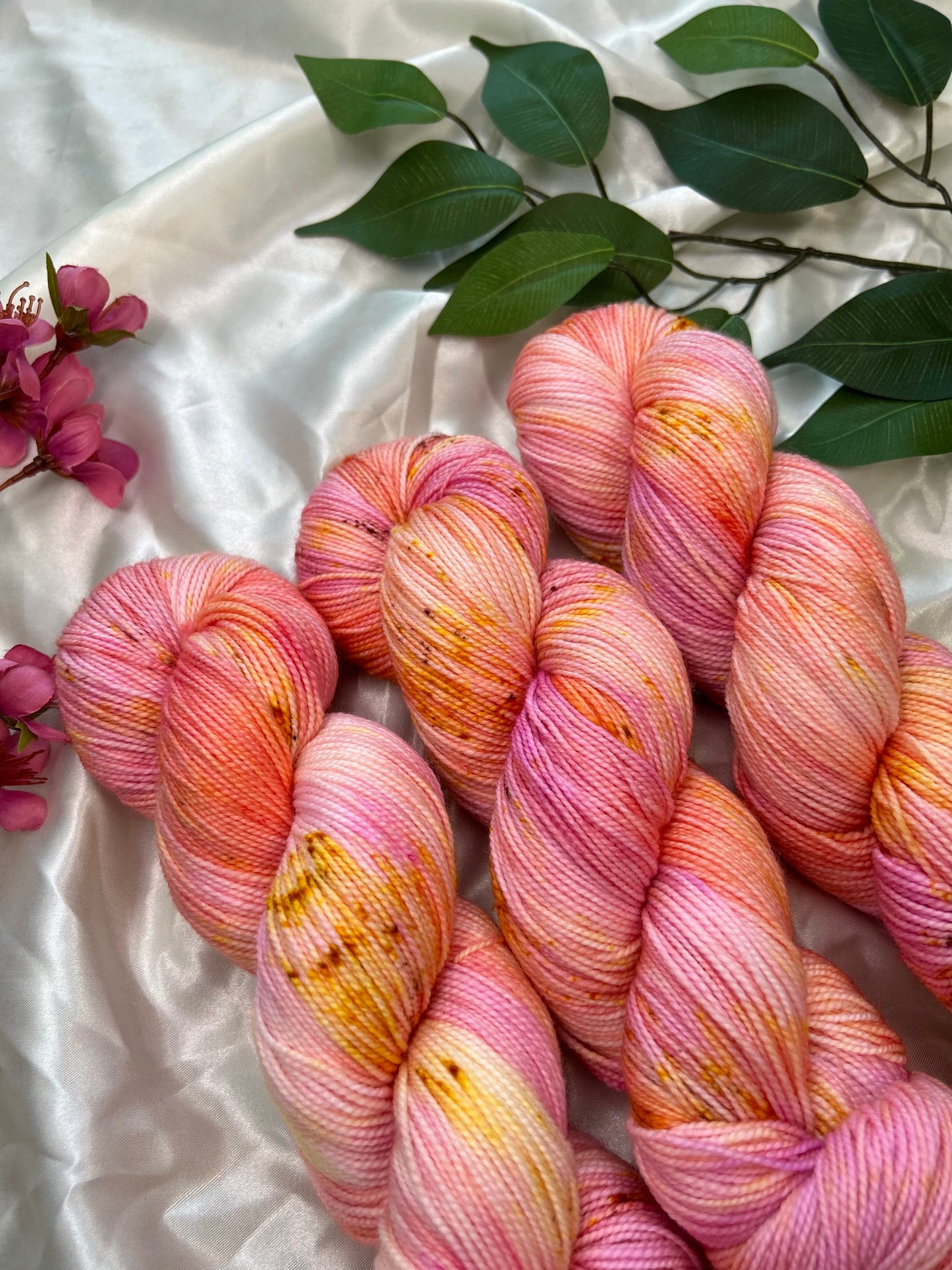 variegated hand dyed yarn in corals, pinks, and pastel orange with fawn brown speckles on nylon sock fiber