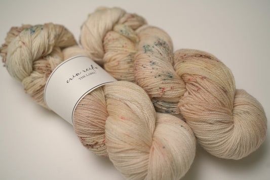 custom variegated hand dyed yarn with soft browns and creamy gold with sage green and mocha brown speckles on superwash fingering weight yarn