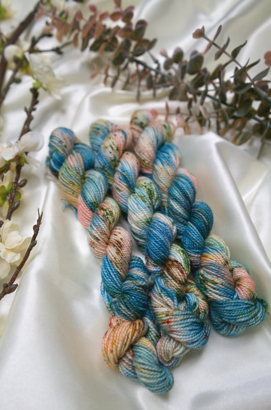 custom variegated hand dyed yarn with teal, cream and salmon pink with fawn brown and green speckles on nylon superwash sock weight