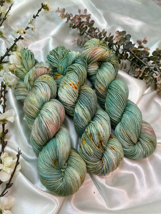 custom sage green, moss green, teal green, pastel salmon pink variegated hand dyed yarn with golden poppy speckles on superwash merino fingering and dk weight
