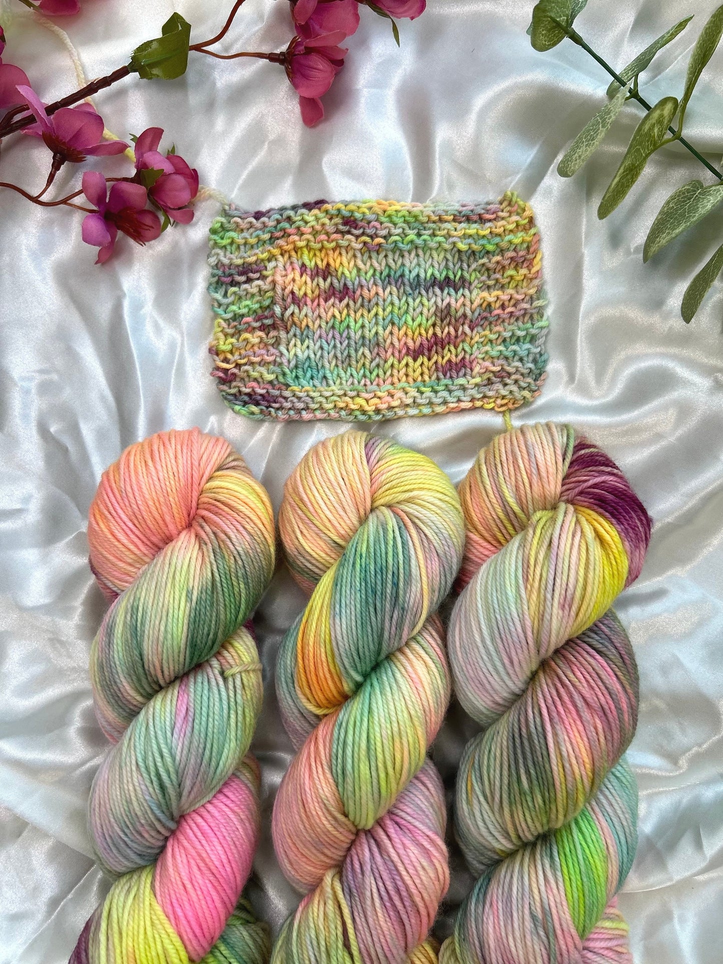 custom pastel rainbow hand dyed yarn with neon pinks, blues, teals and yellow on superwash merino dk weight and knit swatch