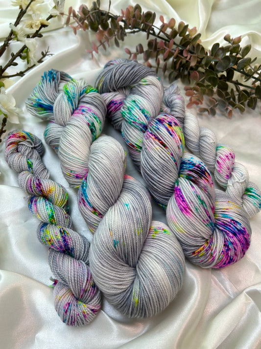 custom grey and white variegated hand dyed yarn with neon pink, blue, green and purple speckles on superwash nylon sport weight