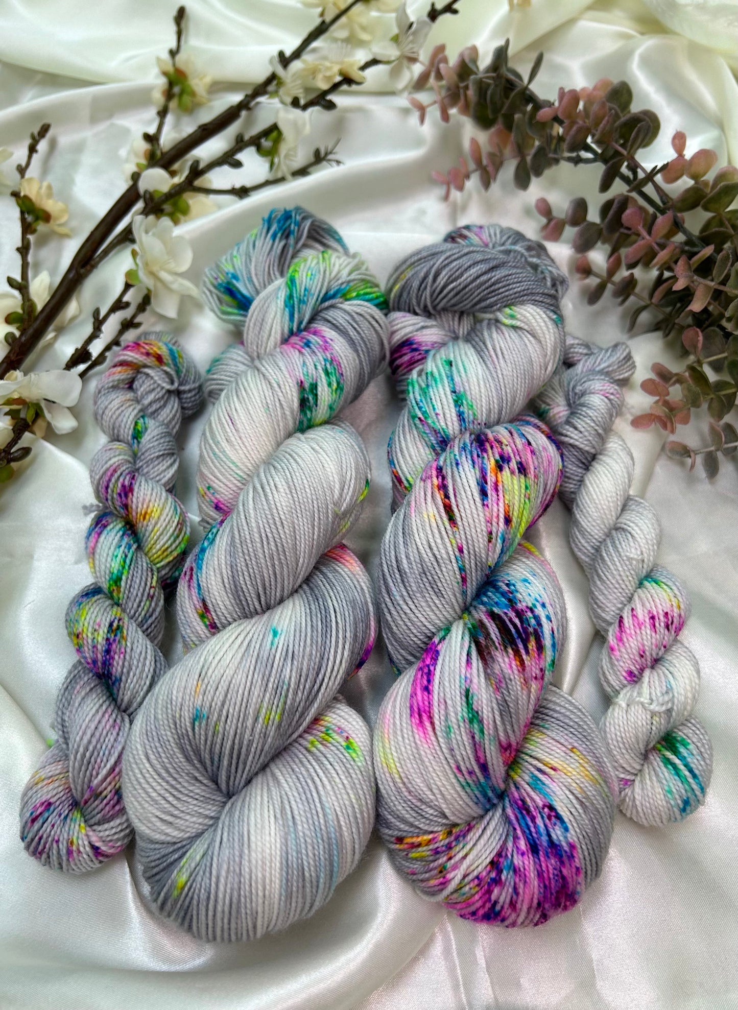 custom grey and white variegated hand dyed yarn with neon pink, blue, green and purple speckles on superwash nylon sport weight