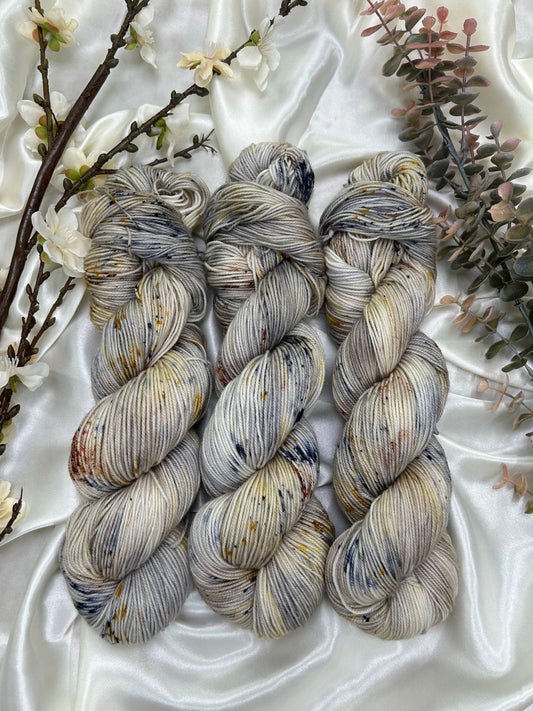 custom navy blue, grey, sepia variegated hand dyed yarn with gold, yellow and cocoa brown speckles on superwash nylon sock weight