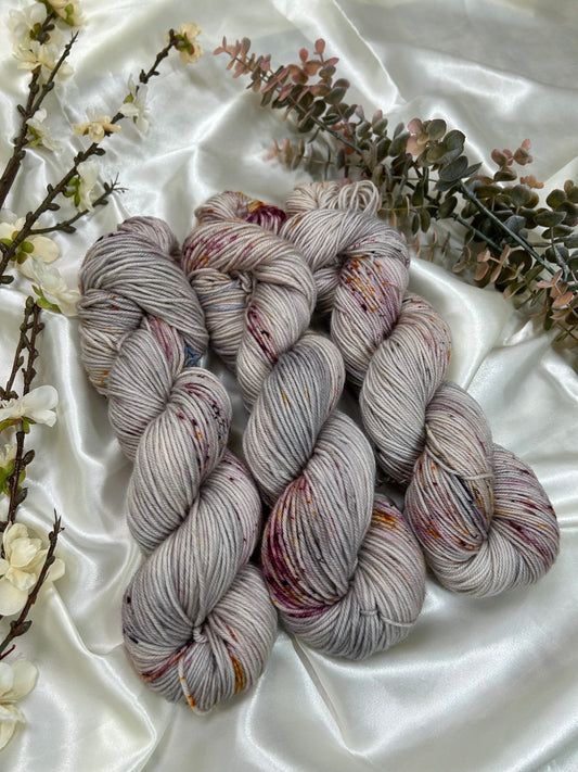 custom grey, silver purple, greige variegated hand dyed yarn with burgundy and gold speckles on superwash merino dk weight