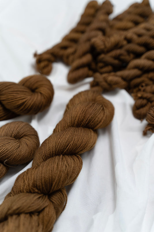 Brown yarn skeins on a white fabric background
