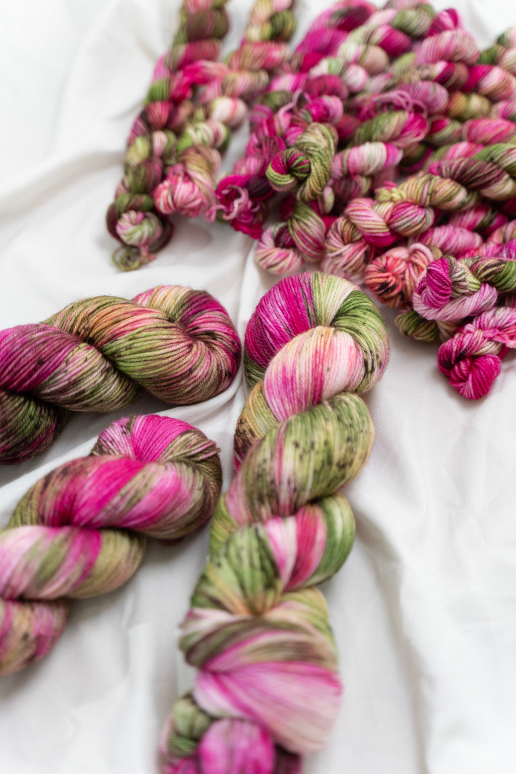 Colorful skeins of yarn in pink and green on a white background