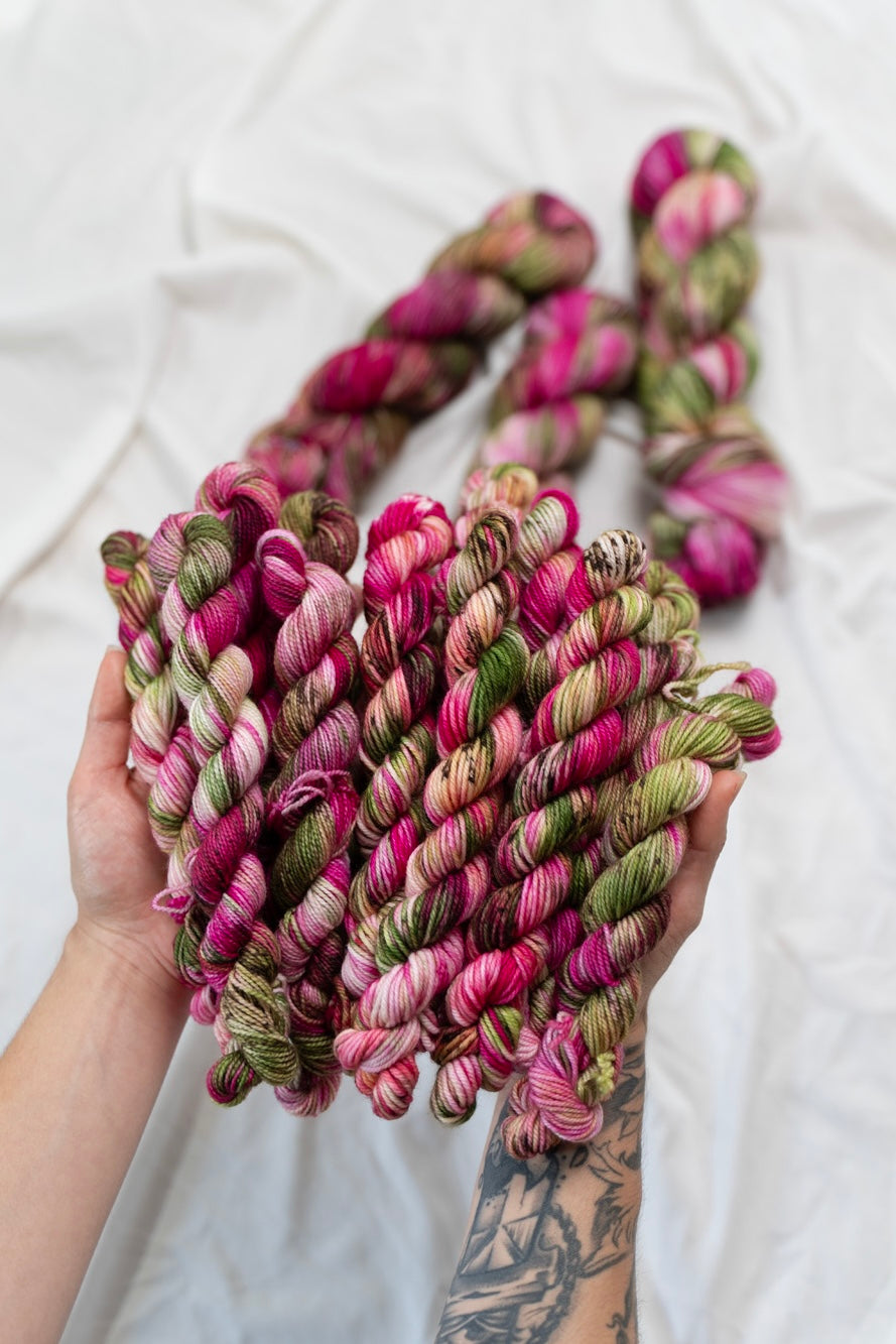 Hand holding multicolored yarn skeins on a white background