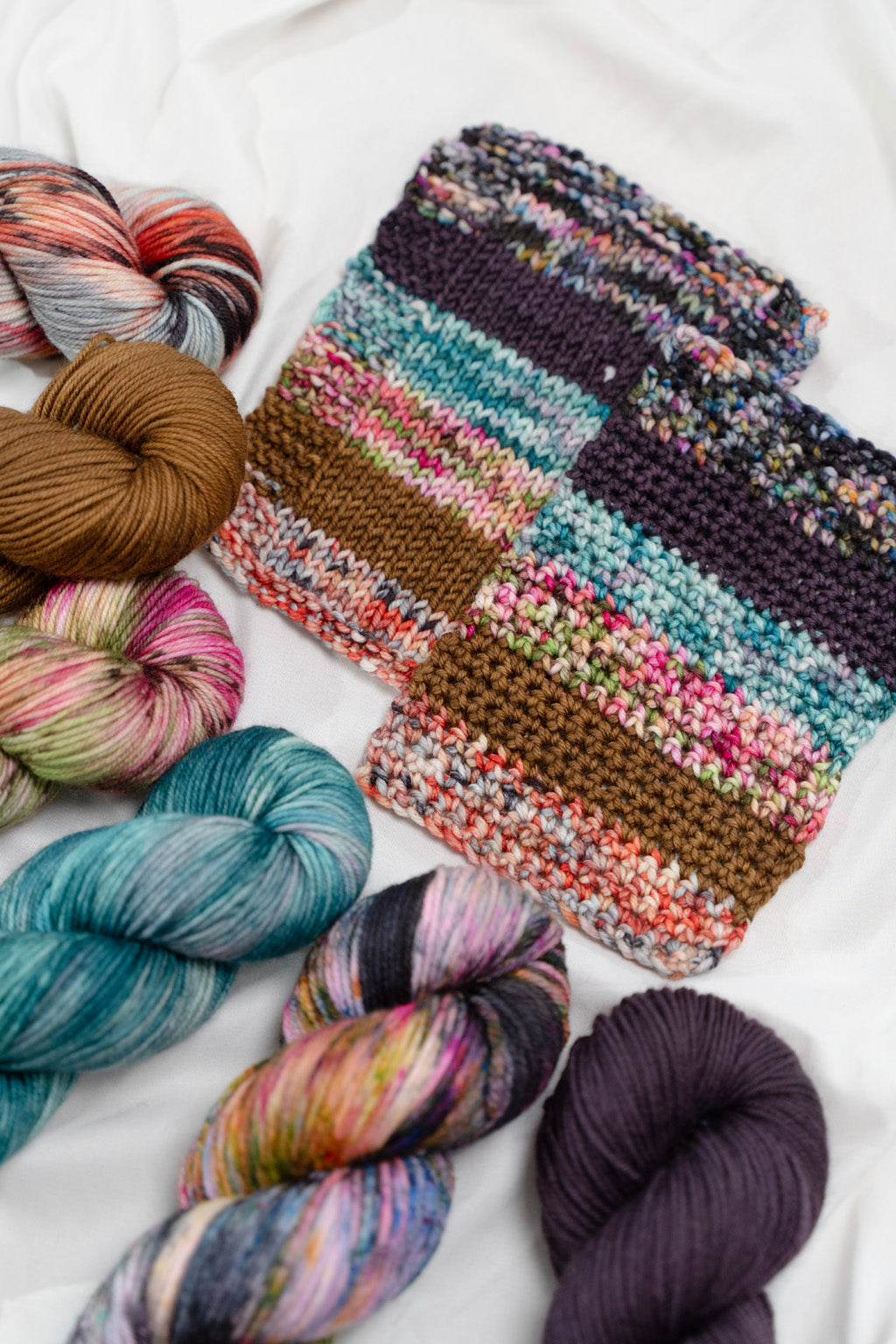 Colorful yarn skeins and a crochet and knit swatch on a white background