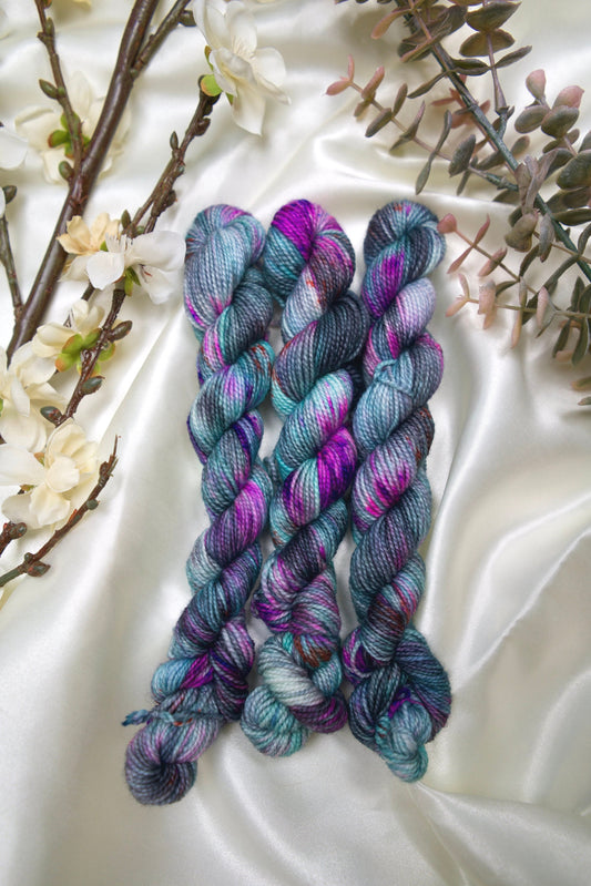 custom variegated hand dyed yarn with grey, black, and teal with neon purple speckles on nylon superwash sock weight