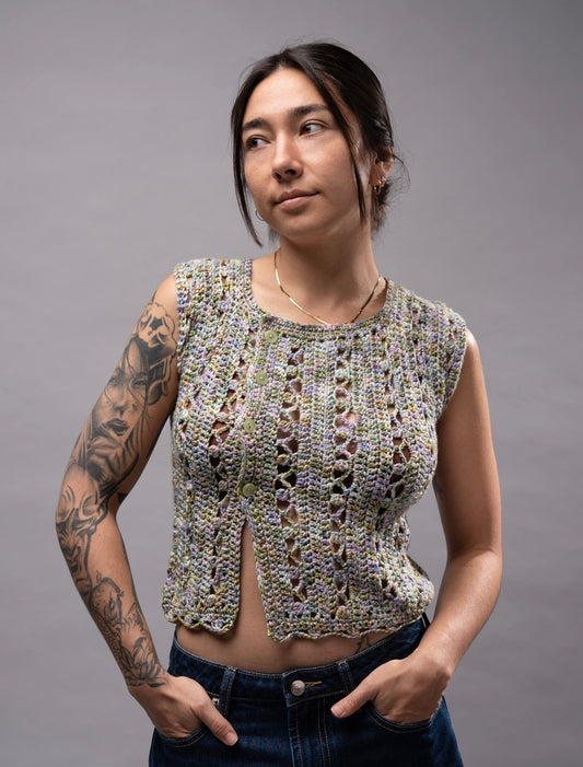 Woman wearing a sleeveless crochet top against a gray background