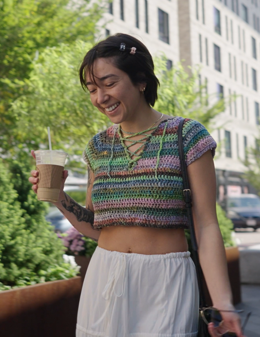 Erin wearing a colorful v-neck crochet top featuring a raglan design and laced center.