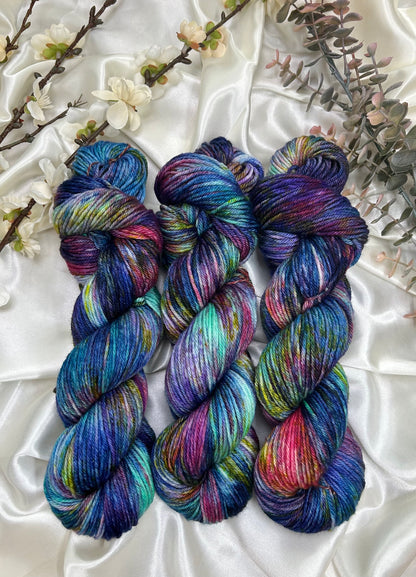 custom variegated hand dyed yarn with midnight blue, violet, teal and deep pink with yellow and green speckles on superwash merino yarn dk weight