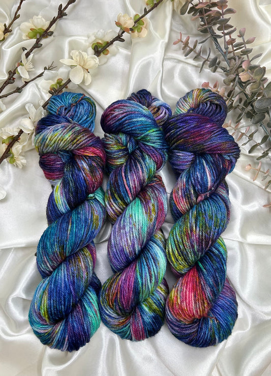 custom variegated hand dyed yarn with midnight blue, violet, teal and deep pink with yellow and green speckles on superwash merino yarn dk weight