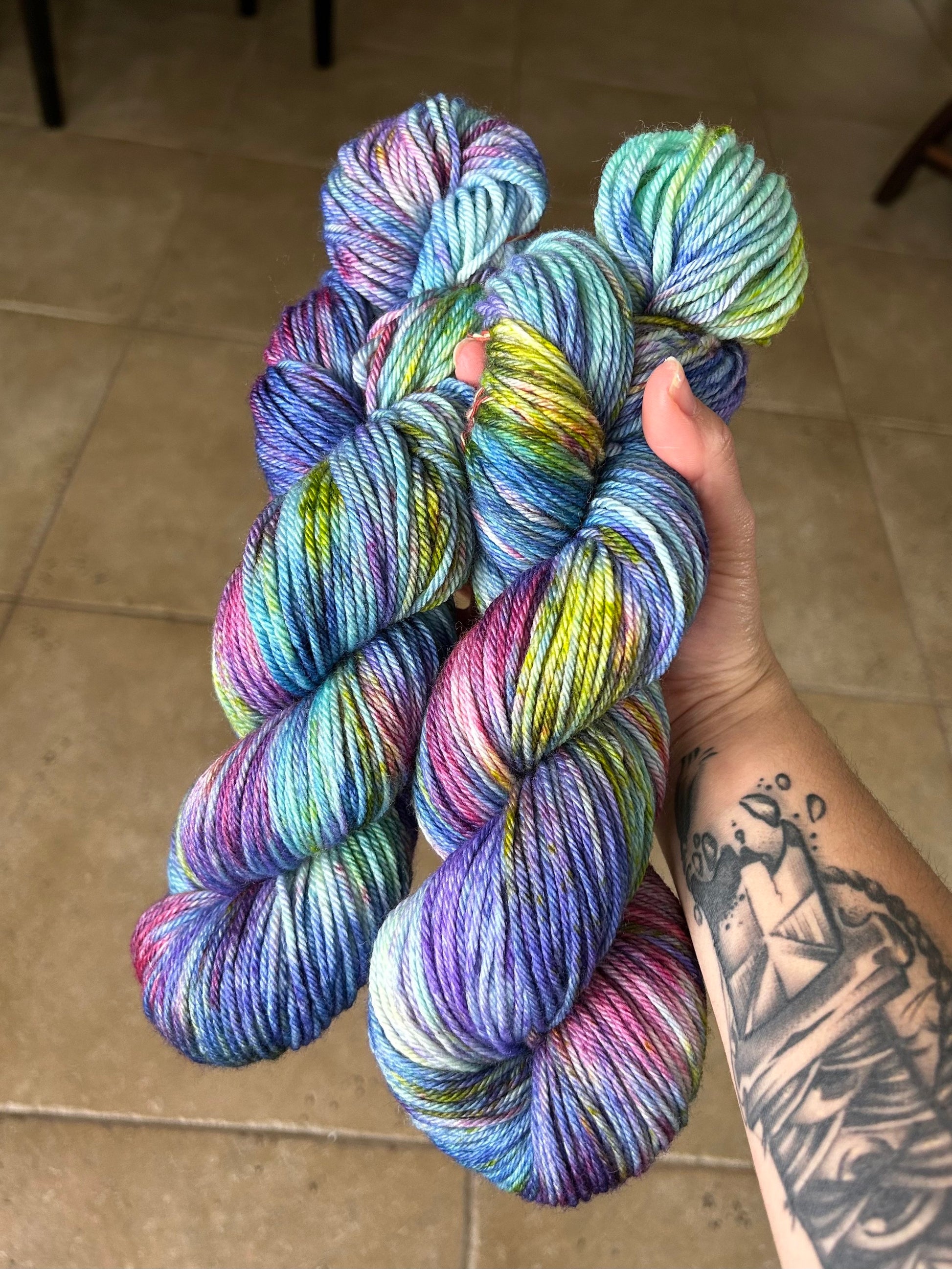 custom variegated hand dyed yarn with midnight blue, violet, teal and deep pink with yellow and green speckles on superwash merino yarn dk weight