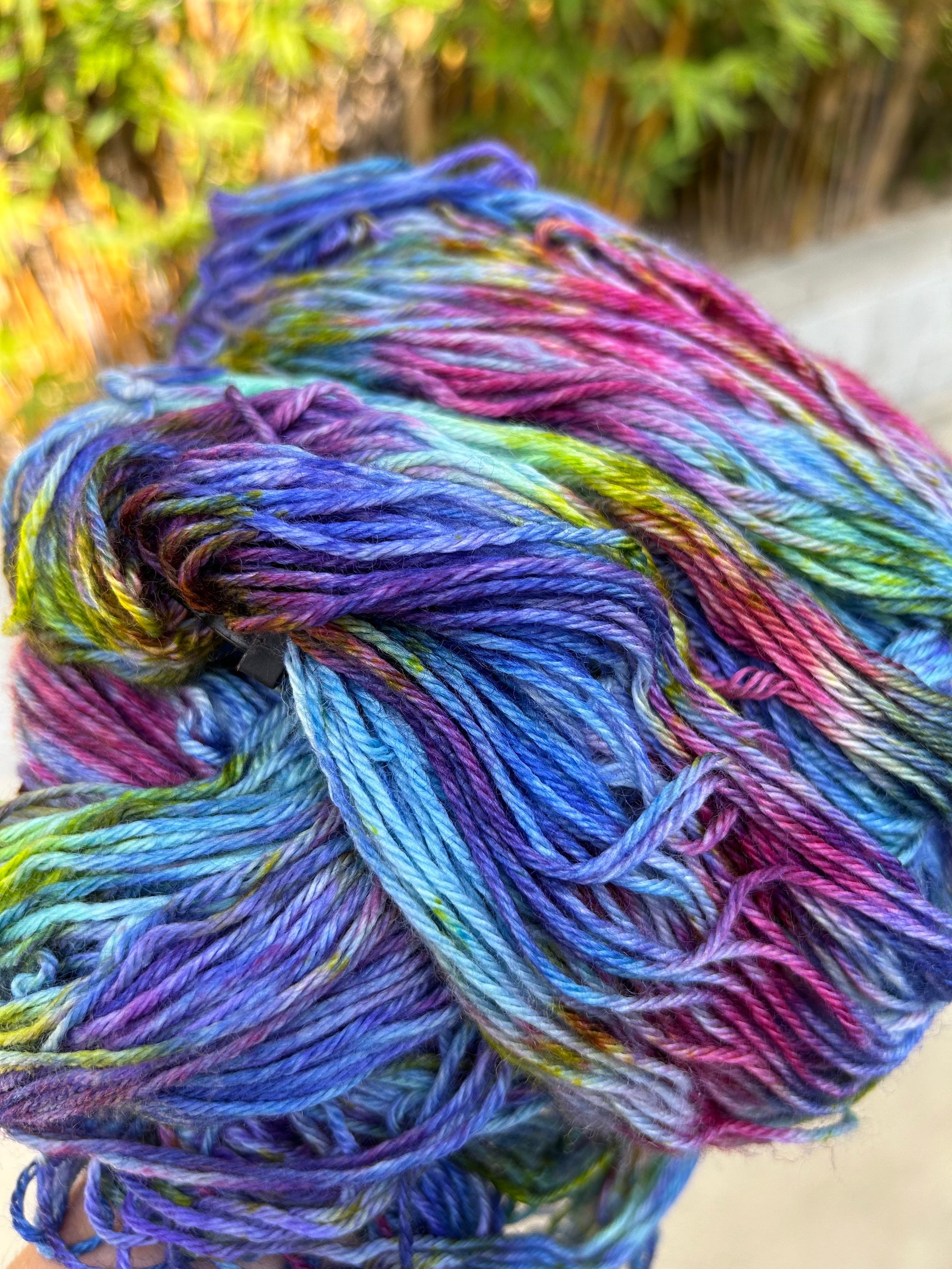 custom variegated hand dyed yarn with midnight blue, violet, teal and deep pink with yellow and green speckles on superwash merino yarn dk weight