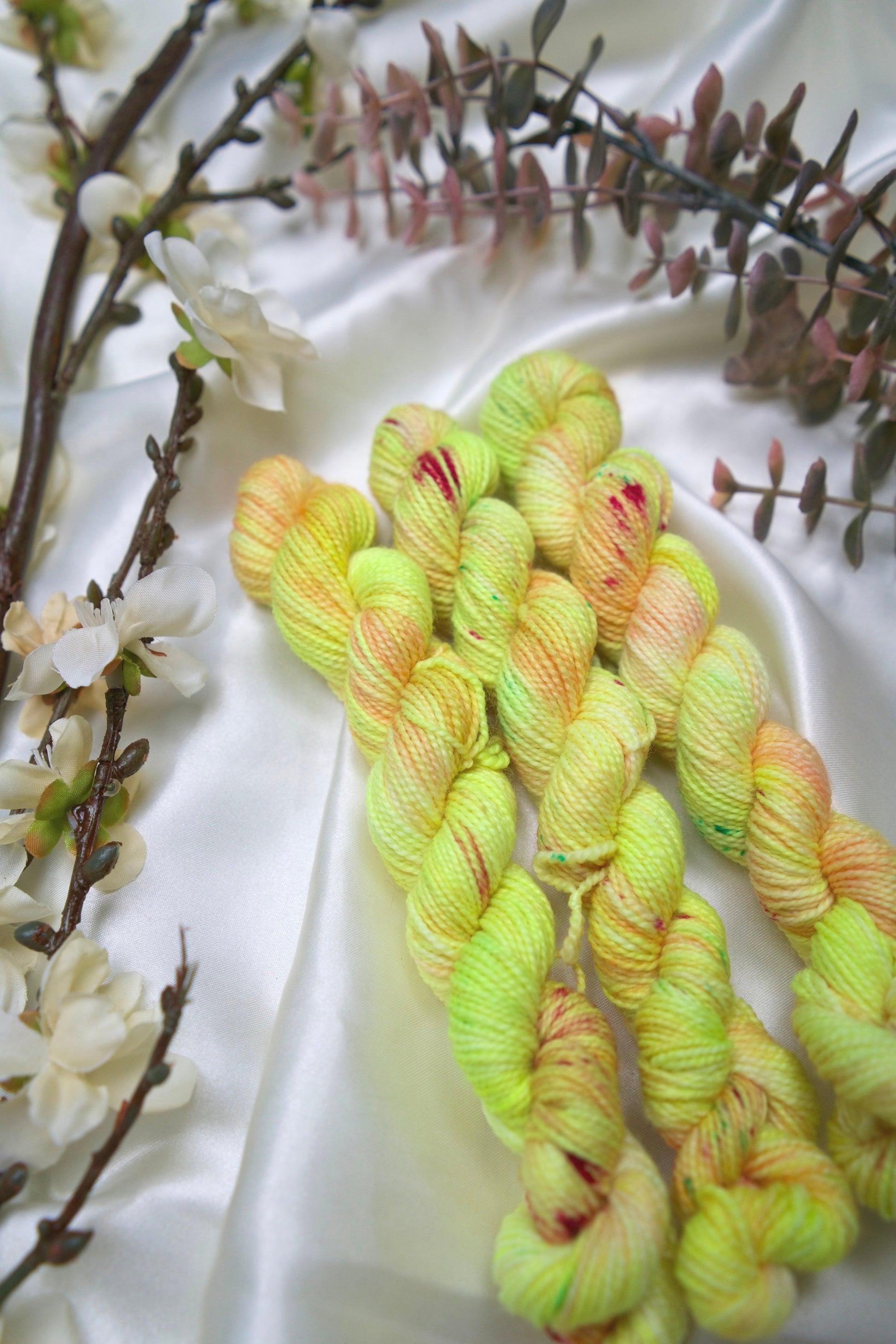 custom variegated hand dyed yarn with neon yellow and pastel peach with cherry red and green speckles on nylon superwash sock yarn