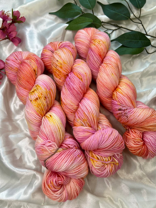 variegated hand dyed yarn in corals, pinks, and pastel orange with fawn brown speckles on nylon sock fiber