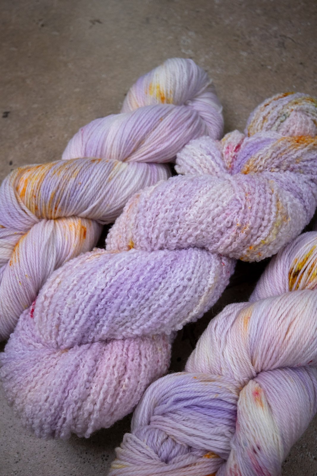 custom variegated hand dyed yarn with pastel lilac and soft purple with gold, orange and cherry red speckles on superwash merino yarn fingering weight