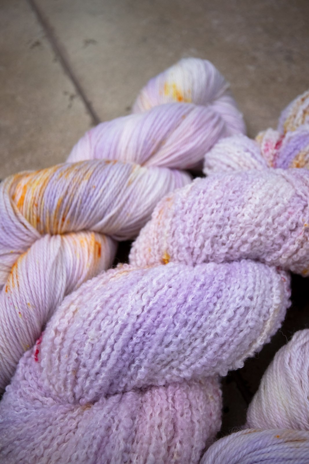 custom variegated hand dyed yarn with pastel lilac and soft purple with gold, orange and cherry red speckles on superwash merino yarn fingering weight
