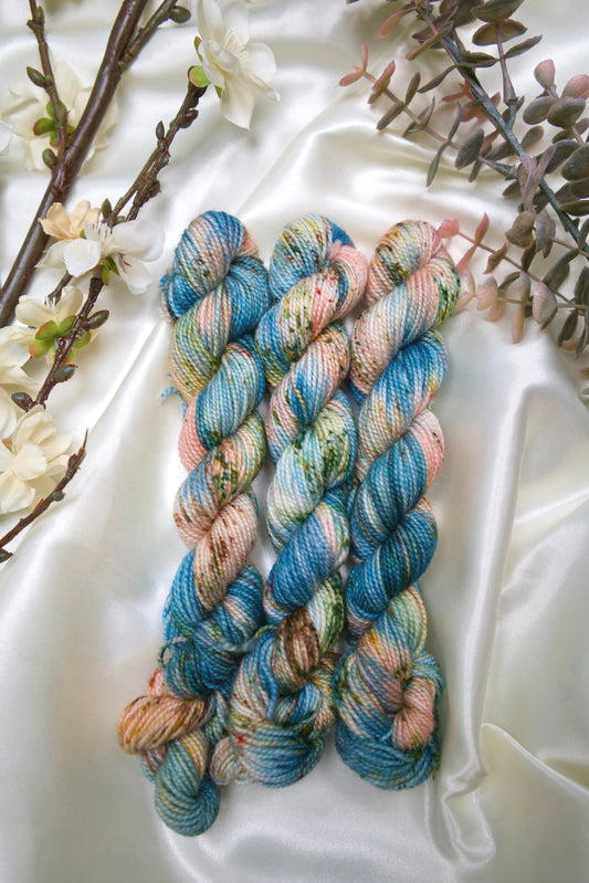 custom variegated hand dyed yarn with teal, cream and salmon pink with fawn brown and green speckles on nylon superwash sock weight