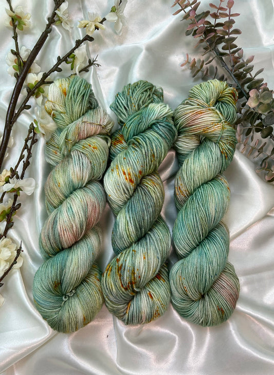 custom sage green, moss green, teal green, pastel salmon pink variegated hand dyed yarn with golden poppy speckles on superwash merino fingering and dk weight