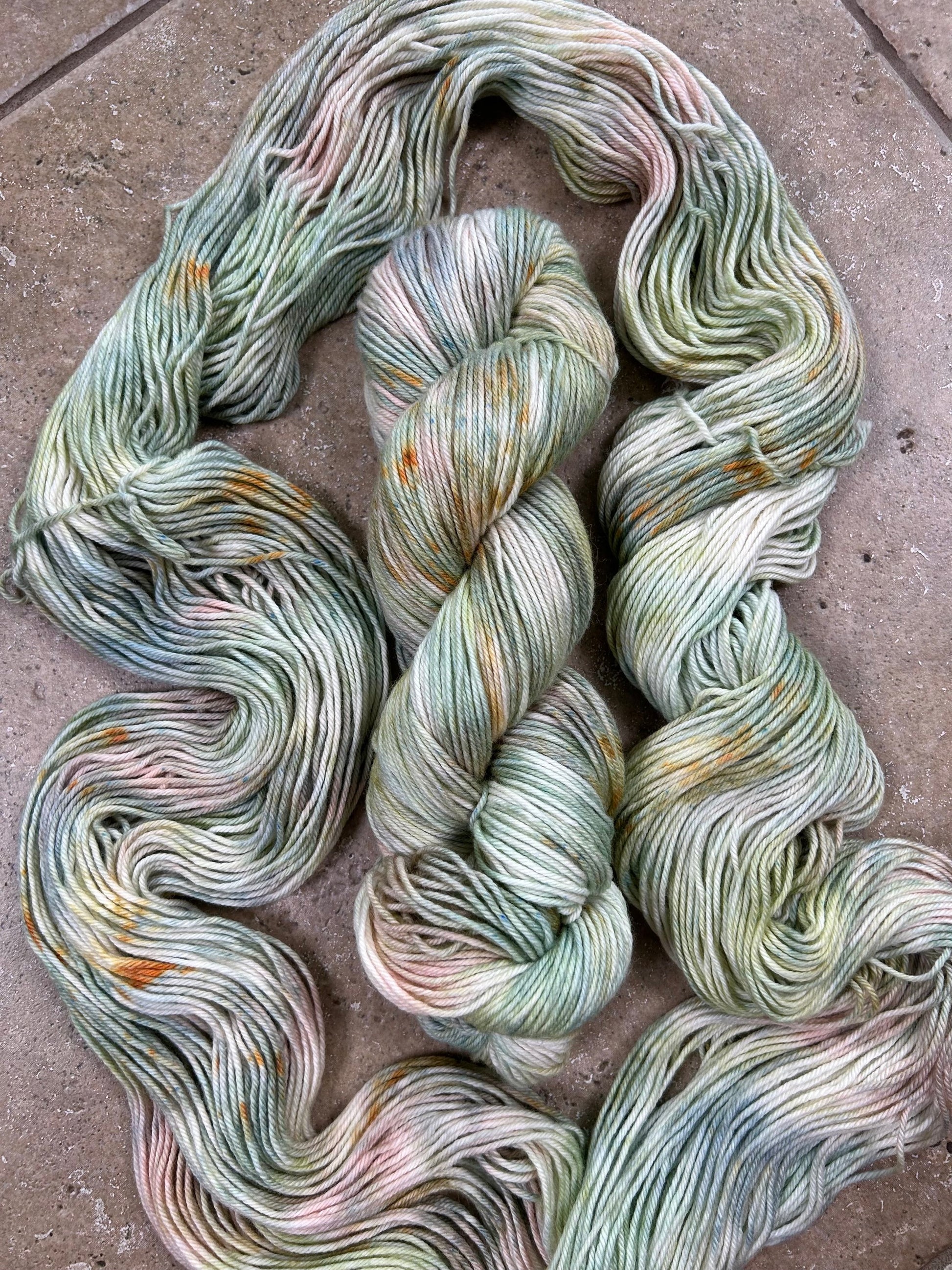custom sage green, moss green, teal green, pastel salmon pink variegated hand dyed yarn with golden poppy speckles on cotton superwash dk weight