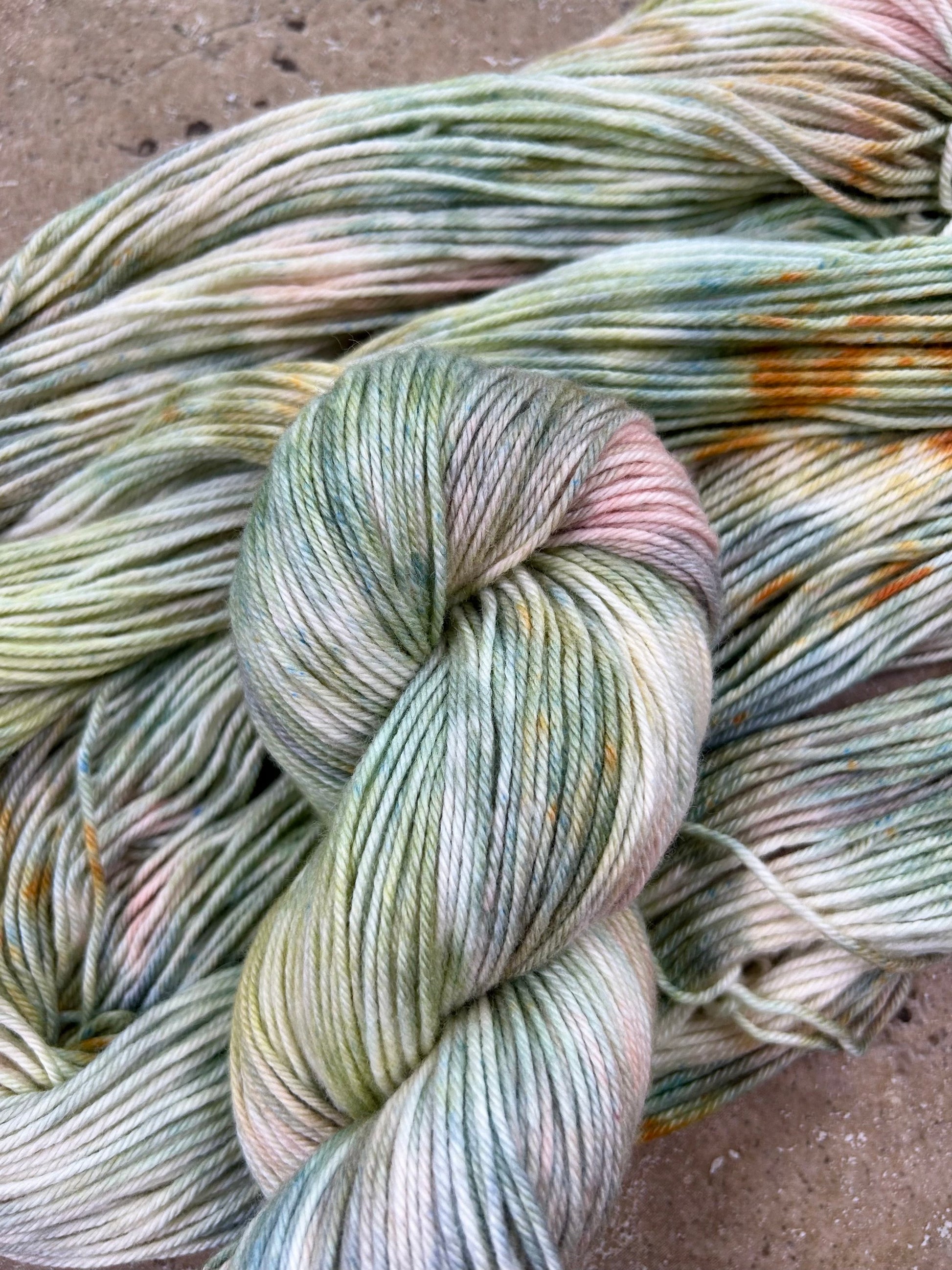 custom sage green, moss green, teal green, pastel salmon pink variegated hand dyed yarn with golden poppy speckles on cotton superwash dk weight