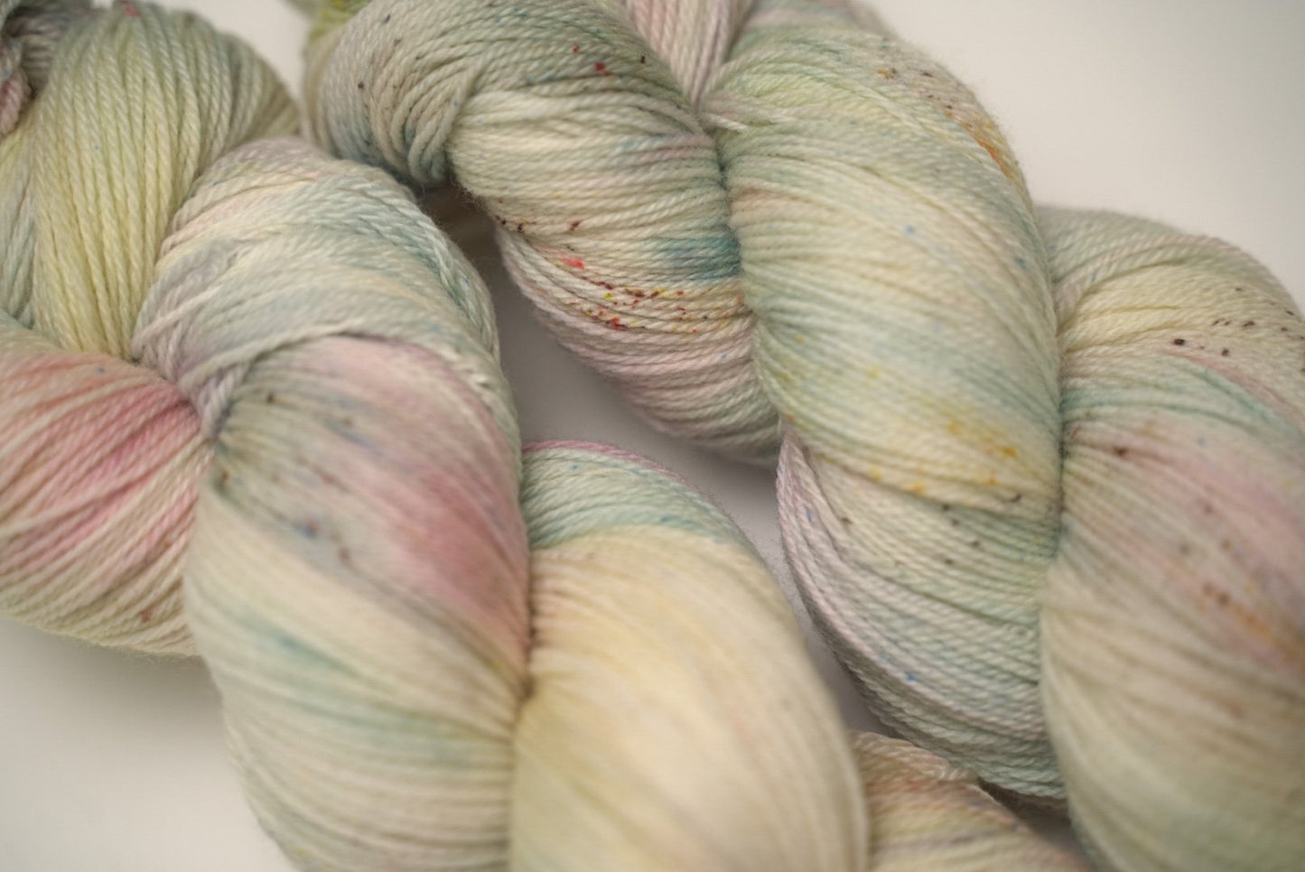 custom mint, sage green, flamingo pink, pastel yellow variegated hand dyed yarn with light cocoa brown speckles on superwash merino fingering weight
