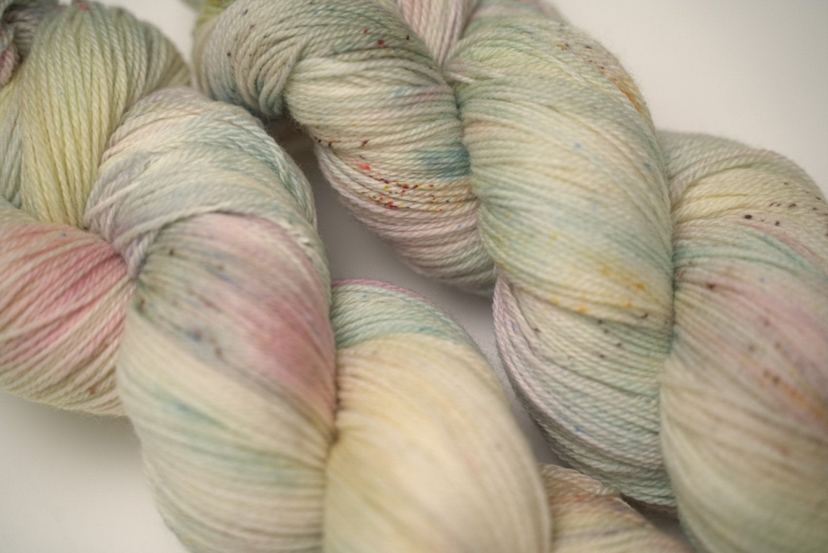 custom mint, sage green, flamingo pink, pastel yellow variegated hand dyed yarn with light cocoa brown speckles on superwash merino fingering weight