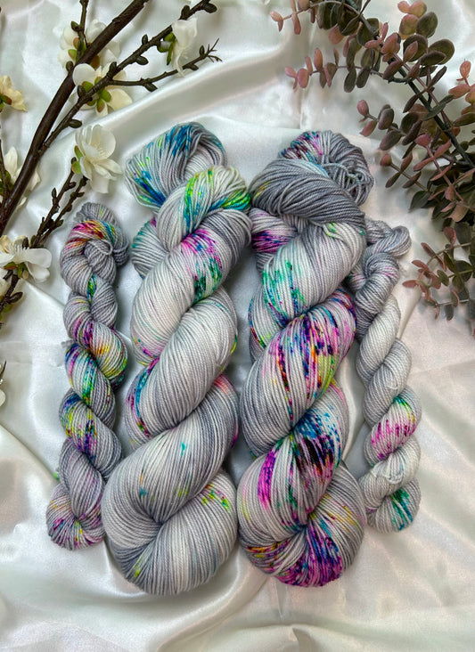 custom grey and white variegated hand dyed yarn with neon pink, blue, green and purple speckles on superwash nylon sport weight