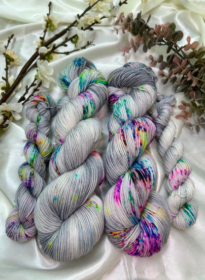 custom grey and white variegated hand dyed yarn with neon pink, blue, green and purple speckles on superwash nylon sport weight