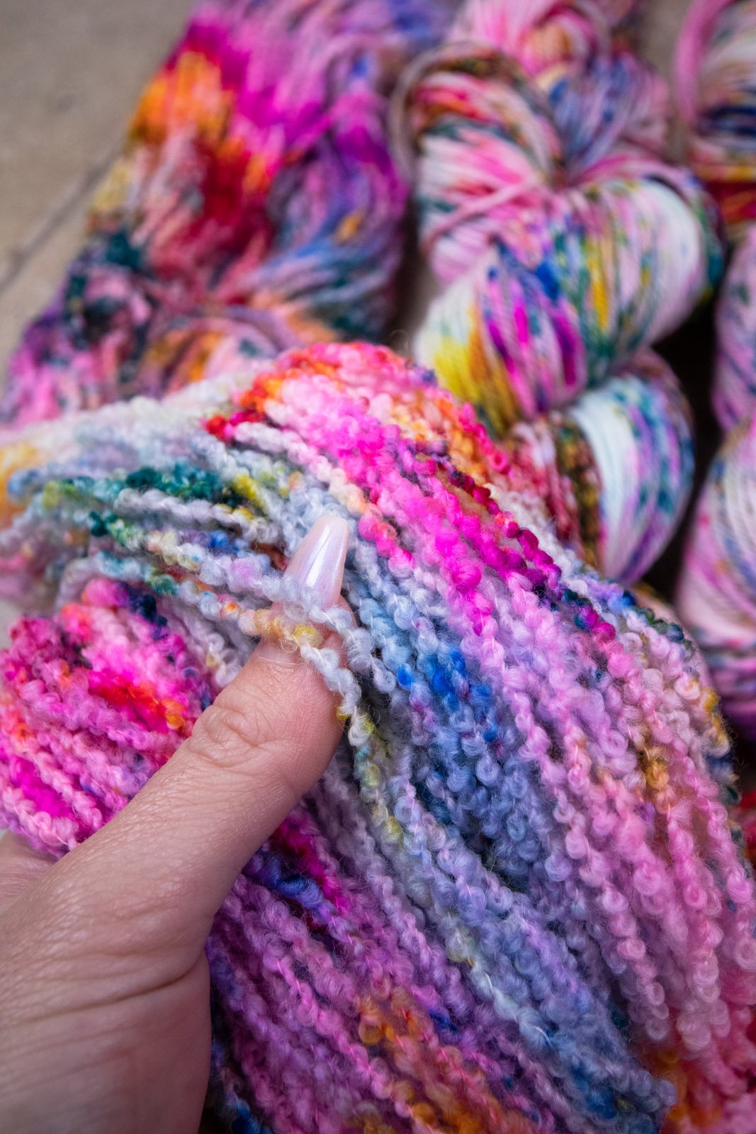 custom variegated hand dyed yarn with blue, neon pink, lichen, magenta, cherry red and yellow speckles on superwash merino boucle yarn