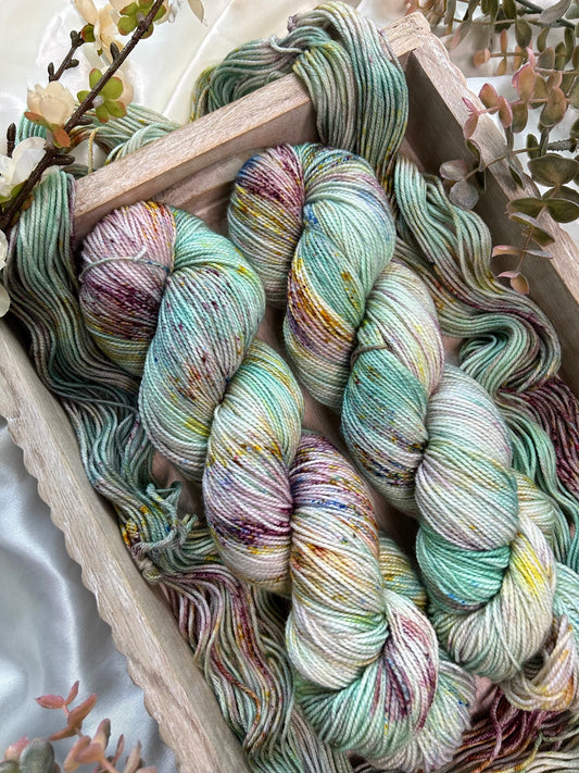 custom aqua, light teal, mint green, cream variegated hand dyed yarn with burgundy, gold, and indigo blue speckles on superwash nylon sport weight