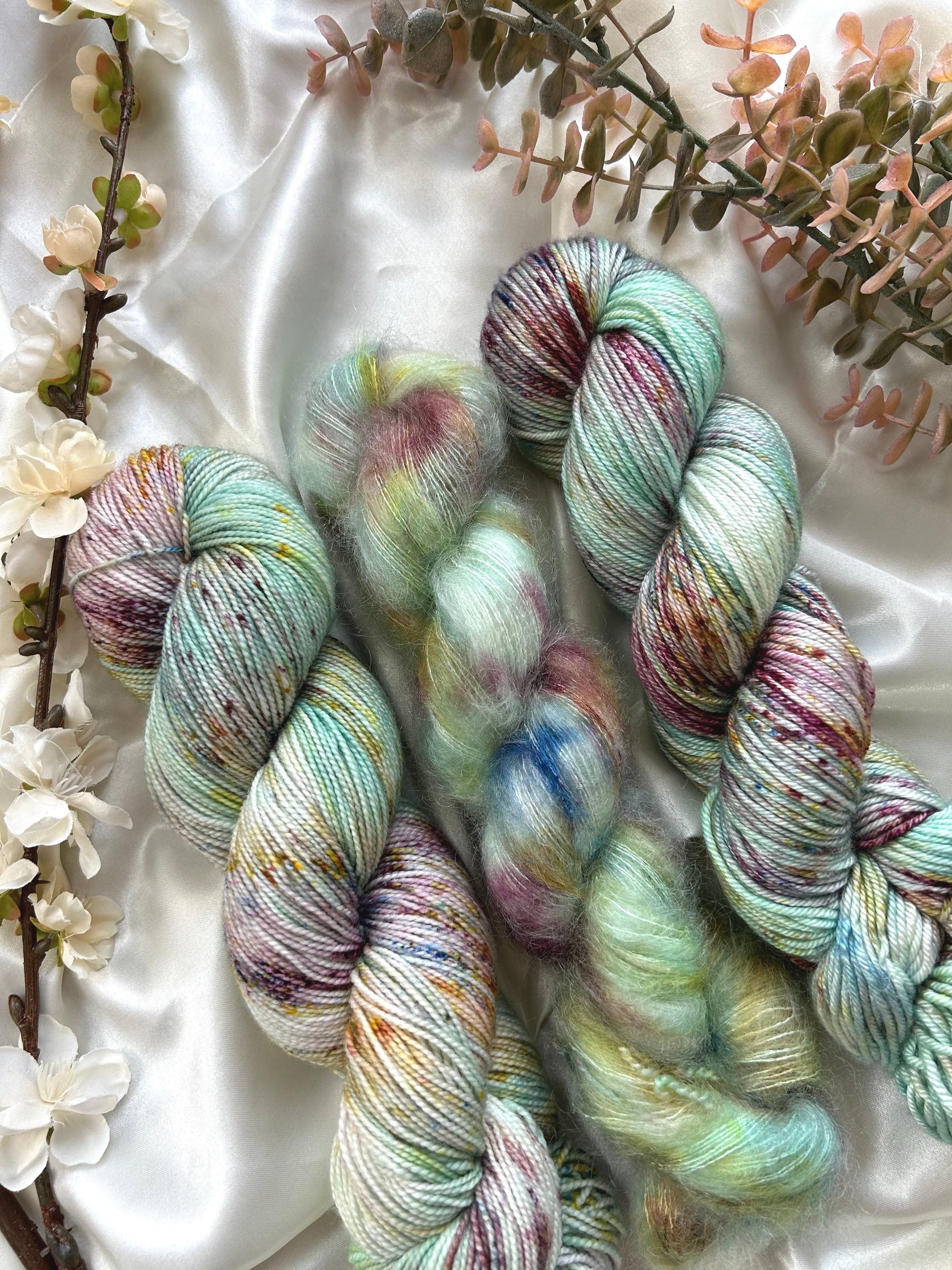 custom aqua, light teal, mint green, cream variegated hand dyed yarn with burgundy, gold, and indigo blue speckles on superwash nylon sport weight, silk dk and kid silk mohair