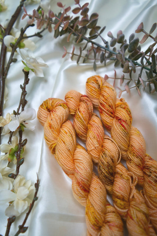 custom peach and cream orange variegated hand dyed yarn with brown, yellow and gold speckles on nylon superwash sock weight