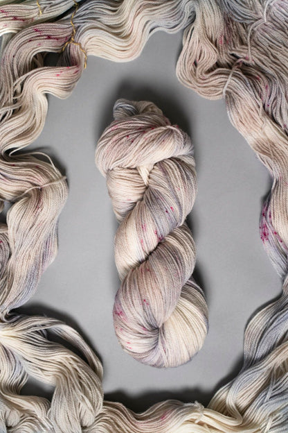 custom periwinkle, blue, purple, tan, beige variegated hand dyed yarn with hot pink speckles on superwash merino fingering weight