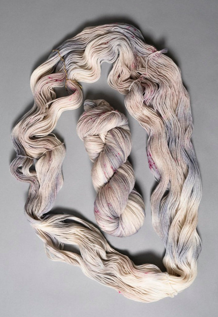 custom periwinkle, blue, purple, tan, beige variegated hand dyed yarn with hot pink speckles on superwash merino fingering weight