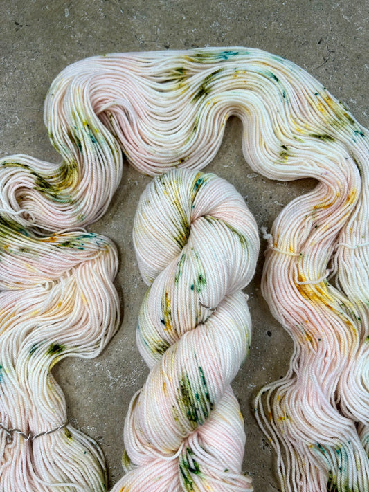 custom pastel baby pink variegated hand dyed yarn with forest green and gold speckles on nylon superwash merino sock 