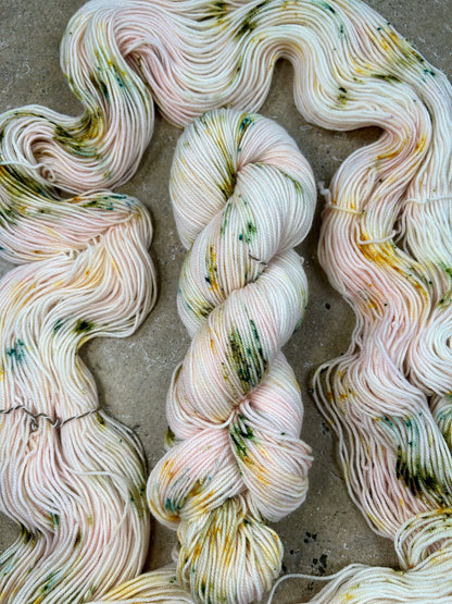 custom pastel baby pink variegated hand dyed yarn with forest green and gold speckles on nylon superwash merino sock 