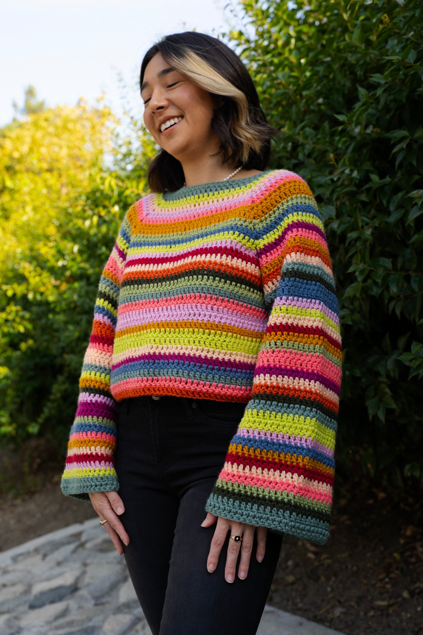 erin wearing a bright striped crochet sweater using a raglan top down design