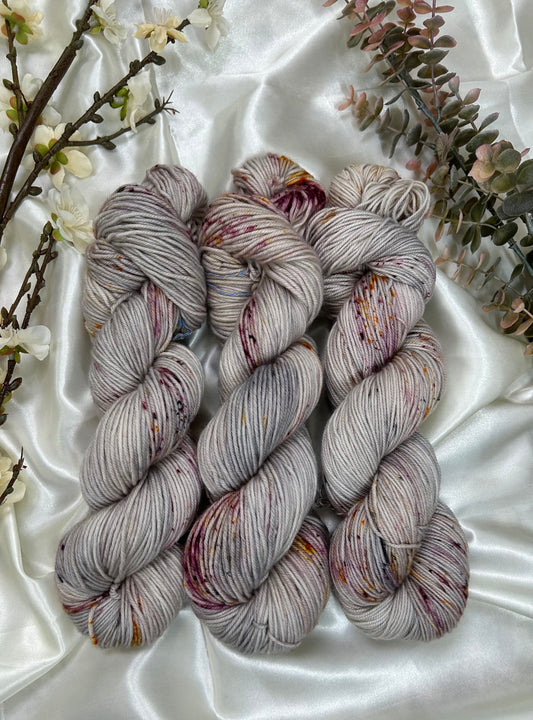 custom grey, silver purple, greige variegated hand dyed yarn with burgundy and gold speckles on superwash merino dk weight