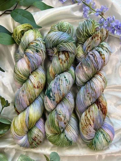 custom lilac, green, dark green, gold variegated hand dyed yarn with forest green and fawn brown speckles on nylon superwash sock weight