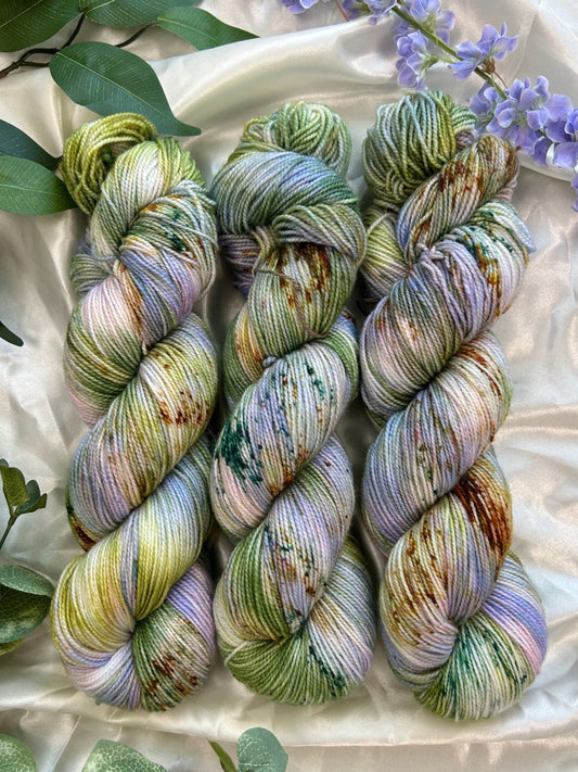 custom lilac, green, dark green, gold variegated hand dyed yarn with forest green and fawn brown speckles on nylon superwash sock weight